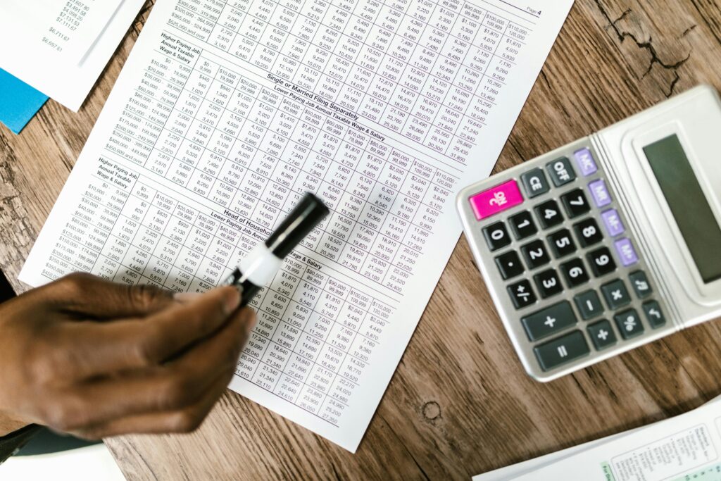 Reviewing a weekly cash flow forecast with a calculator and pen